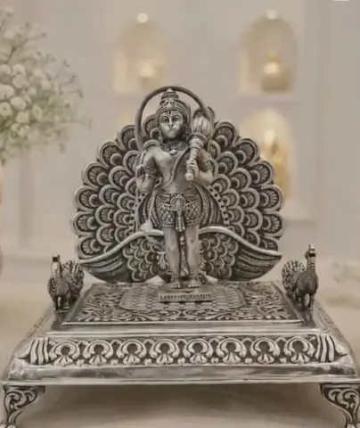 Silver Hanuman idol before a peacock arch on a silver base